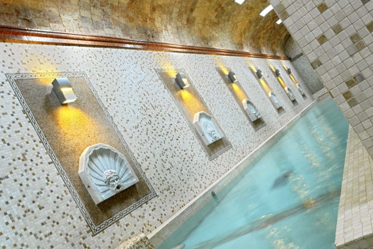 Klasszikus stílusú wellness medence mozaikburkolattal és díszes vízkiömlő elemekkel.