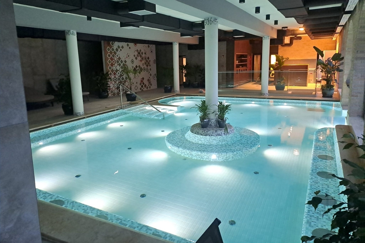 Luxus hotel beltéri wellness medencéje mozaikburkolattal, elegáns világítással és prémium kivitelezéssel.