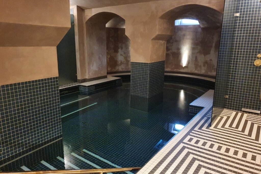 Íves kialakítású mozaik burkolatú medence egyedi formákkal és lépcsőkkel