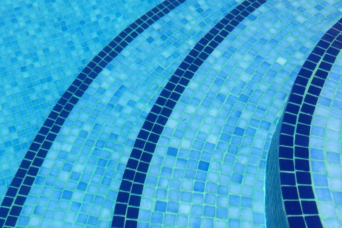 Íves kialakítású mozaik burkolatú medence lépcső közelről